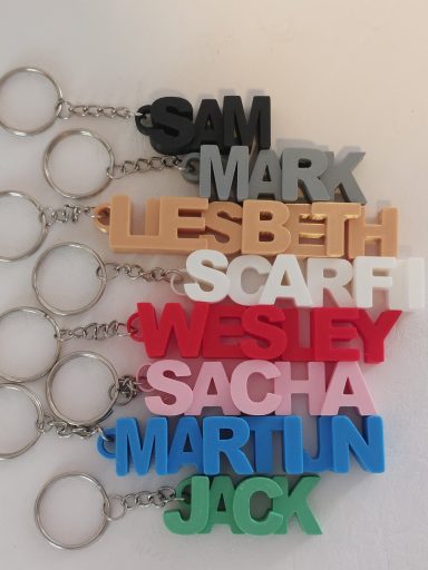 Kleurrijke keychains met de namen Sam, Mark, Liesbeth, Scarfi, Wesley, Sacha, Martin en Jack.